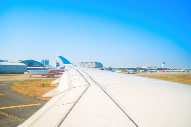Havaalanının penceresinden Tan Son Nhat 'i izleyin. Mavi gökyüzü ve uçak penceresi manzaralı tüylü beyaz bulutlar, jet motoru kanatta. Uçak bileti rezervasyonu. Pencere kenarı. Seçici odak