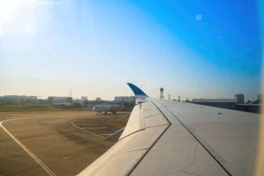 Havaalanının penceresinden Tan Son Nhat 'i izleyin. Mavi gökyüzü ve uçak penceresi manzaralı tüylü beyaz bulutlar, jet motoru kanatta. Uçak bileti rezervasyonu. Pencere kenarı. Seçici odak