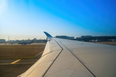 Havaalanının penceresinden Tan Son Nhat 'i izleyin. Mavi gökyüzü ve uçak penceresi manzaralı tüylü beyaz bulutlar, jet motoru kanatta. Uçak bileti rezervasyonu. Pencere kenarı. Seçici odak