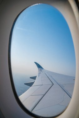 Havaalanının penceresinden Tan Son Nhat 'i izleyin. Mavi gökyüzü ve uçak penceresi manzaralı tüylü beyaz bulutlar, jet motoru kanatta. Uçak bileti rezervasyonu. Pencere kenarı. Seçici odak