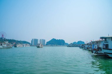 Bai Chay köprüsü ve güneş tekerleği sabahın erken saatlerinde Ha Long, Vietnam 'da güzel bulutlarla. Marina, Boats, Ferris Wheel ve Askı Köprüsü. Hepsi Bai Chay Sahili 'nde.