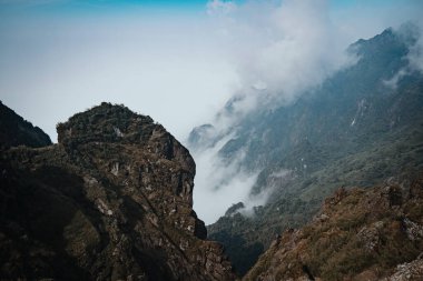 Sapa Hoang Lien Son Dağı 'ndaki Fansipan Dağı' nın zirvesinden Rocky Dağı tepeleri Lao Cai 'deki sisli bulutların arasından çıkar. Manzaralı hava manzarası. Bulutların ya da sislerin üzerinden uç.