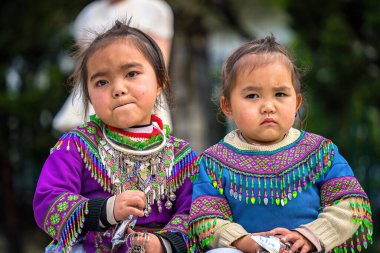 Lao Cai, VIETNAM - MAR 12 2023: Vietnamlı küçük bir kızın güzel portresi HMong etnik azınlığı kilisenin önünde oturan turistleri selamlıyor ve el yapımı eşyalar satıyor. Sapa şehir merkezinde.