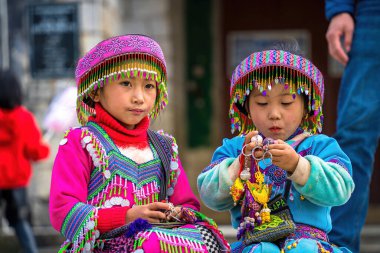 Lao Cai, VIETNAM - MAR 12 2023: Vietnamlı küçük bir kızın güzel portresi HMong etnik azınlığı kilisenin önünde oturan turistleri selamlıyor ve el yapımı eşyalar satıyor. Sapa şehir merkezinde.