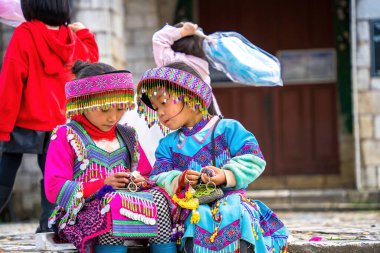 Lao Cai, VIETNAM - MAR 12 2023: Vietnamlı küçük bir kızın güzel portresi HMong etnik azınlığı kilisenin önünde oturan turistleri selamlıyor ve el yapımı eşyalar satıyor. Sapa şehir merkezinde.