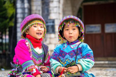 Lao Cai, VIETNAM - MAR 12 2023: Vietnamlı küçük bir kızın güzel portresi HMong etnik azınlığı kilisenin önünde oturan turistleri selamlıyor ve el yapımı eşyalar satıyor. Sapa şehir merkezinde.