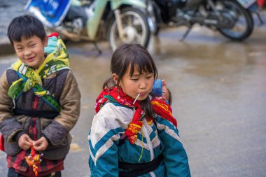 Lao Cai, VIETNAM - MAR 12 2023: Vietnamlı küçük bir kızın güzel portresi HMong etnik azınlığı kilisenin önünde oturan turistleri selamlıyor ve el yapımı eşyalar satıyor. Sapa şehir merkezinde.