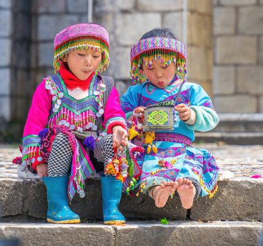 Lao Cai, VIETNAM - MAR 12 2023: Vietnamlı küçük bir kızın güzel portresi HMong etnik azınlığı kilisenin önünde oturan turistleri selamlıyor ve el yapımı eşyalar satıyor. Sapa şehir merkezinde.