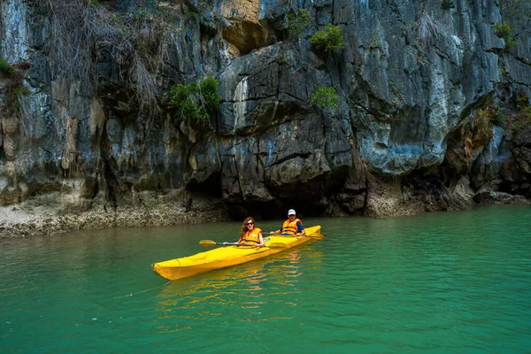 stock image Ha Long, VIETNAM MAR 12 2023: Tourist junks floating among limestone rocks at Ha Long Bay, people kayaking inside of a cave in Lan Ha Bay, close to Halong Bay, Vietnam