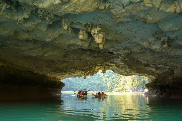Ha Long, VİETNAM MAR 12 2023: Ha Long Körfezi 'ndeki kireçtaşı kayaların arasında yüzen turist hurdaları, Halong Körfezi, Vietnam yakınlarındaki Lan Ha Körfezi' ndeki bir mağarada kano yapan insanlar.