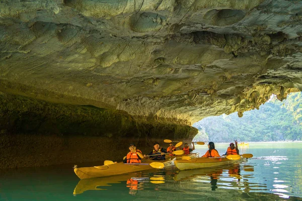 stock image Ha Long, VIETNAM MAR 12 2023: Tourist junks floating among limestone rocks at Ha Long Bay, people kayaking inside of a cave in Lan Ha Bay, close to Halong Bay, Vietnam