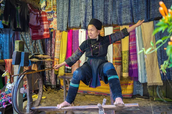Lao Cai - VİETNAM MAR 12 2023: Yaşlı H 'mong kadını dikiş makineleriyle geleneksel H' mong kostümleri yapıyor. Ulusal kıyafetler, giysilerdeki nakış desenleri, siyah Hmong kabileleri.