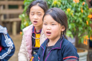 Lao Cai, VIETNAM - MAR 12 2023: Vietnamlı küçük bir oğlan ve kız HMong etnik azınlığının güzel portresi Sapa şehir merkezinde turistleri selamlıyor