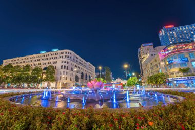 Ho Chi Minh, VİETNAM - 14 MAR 2023: Nguyen Hue caddesinde Ho Chi Minh heykeli ve Ho Chi Minh Halk Komitesi önünde yürüyen güzel ışıklı nilüfer çeşmesi