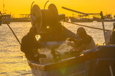 Vung Tau, VIETNAM MAR 25 2023: Balıkçı ağlarını gün doğumunda ya da günbatımında tekneye atıyor. Geleneksel balıkçılar balık ağını hazırlıyor.