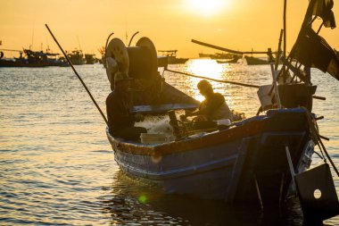 Vung Tau, VIETNAM MAR 25 2023: Balıkçı ağlarını gün doğumunda ya da günbatımında tekneye atıyor. Geleneksel balıkçılar balık ağını hazırlıyor.