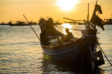 Vung Tau, VIETNAM MAR 25 2023: Balıkçı ağlarını gün doğumunda ya da günbatımında tekneye atıyor. Geleneksel balıkçılar balık ağını hazırlıyor.