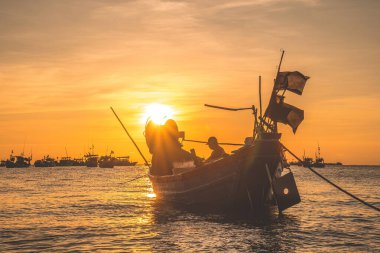 Vung Tau, VIETNAM MAR 25 2023: Balıkçı ağlarını gün doğumunda ya da günbatımında tekneye atıyor. Geleneksel balıkçılar balık ağını hazırlıyor.