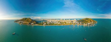 Vung Tau city aerial view with beautiful sunset and so many boats. Panoramic coastal Vung Tau view from above, with waves, coastline, streets, coconut trees and Tao Phung mountain in Vietnam.