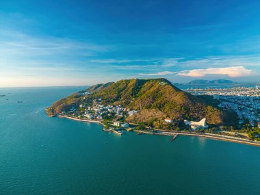 Vung Tau city aerial view with beautiful sunset and so many boats. Panoramic coastal Vung Tau view from above, with waves, coastline, streets, coconut trees and Tao Phung mountain in Vietnam.