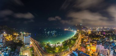 Vung Tau city aerial view with beautiful sunset and so many boats. Panoramic coastal Vung Tau view from above, with waves, coastline, streets, coconut trees and Tao Phung mountain in Vietnam.