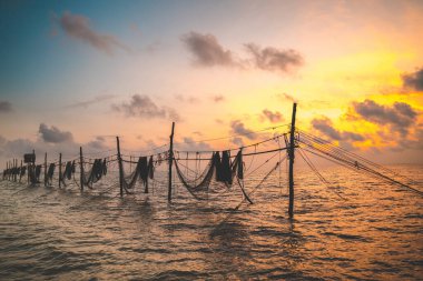 Balıkçıların silueti güneş doğarken oltaya ağ atıyor. Geleneksel balıkçılar balıkçı ağını hazırlıyorlar, yerel halk buna Day hang khoi diyor. Balıkçılık ve günlük yaşam konsepti.
