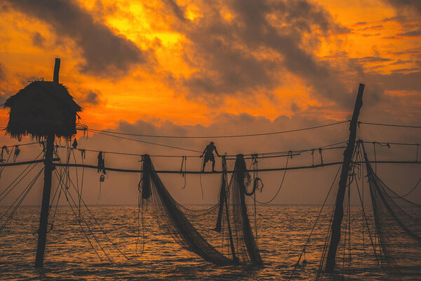 Силуэт рыбаков, бросающих сети на рыболовные палки на восходе солнца. Традиционные рыбаки готовят рыболовные сети, местные жители называют это Дневной висячий хой. Рыболовство и повседневная жизнь.