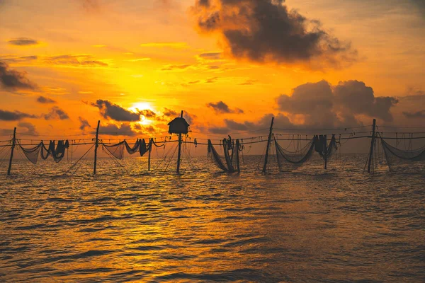 Silhouette of fishermen casting a nets on fishing poles on sunrise. Traditional fishermen prepare the fishing net, local people call it is Day hang khoi. Fisheries and everyday life concept.