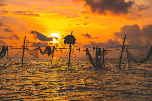 Silhouette of fishermen casting a nets on fishing poles on sunrise. Traditional fishermen prepare the fishing net, local people call it is Day hang khoi. Fisheries and everyday life concept.