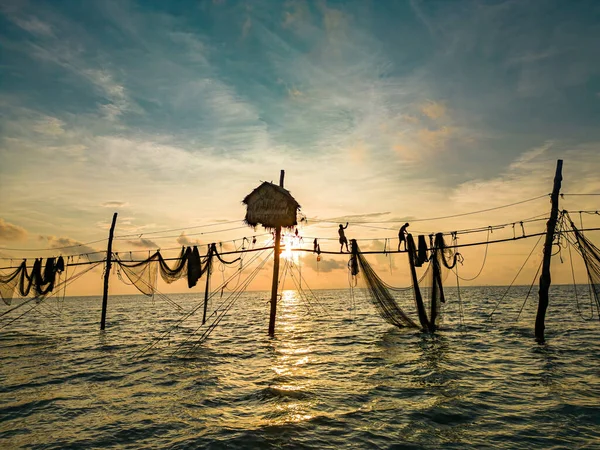 Two fishermen casting a nets on fishing poles on beautiful sunrise. Traditional fishermen prepare the fishing net, local people call it is Day hang khoi. Fisheries and everyday life concept.
