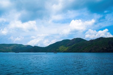 Panoramik sahil kıyısı Con Dao adası yukarıdan, dalgalar, kıyı şeridi, açık gökyüzü ve yol, mavi deniz ve dağ.