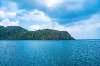 Panoramik sahil kıyısı Con Dao adası yukarıdan, dalgalar, kıyı şeridi, açık gökyüzü ve yol, mavi deniz ve dağ.