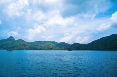 Panoramik sahil kıyısı Con Dao adası yukarıdan, dalgalar, kıyı şeridi, açık gökyüzü ve yol, mavi deniz ve dağ.
