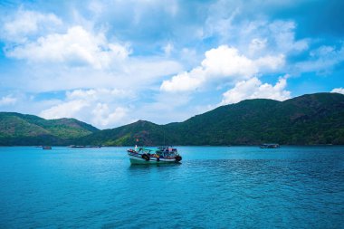 Panoramik sahil kıyısı Con Dao adası yukarıdan, dalgalar, kıyı şeridi, açık gökyüzü ve yol, mavi deniz ve dağ.