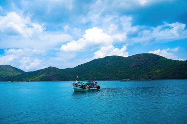 Panoramik sahil kıyısı Con Dao adası yukarıdan, dalgalar, kıyı şeridi, açık gökyüzü ve yol, mavi deniz ve dağ.