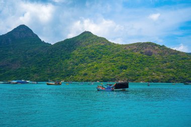 Panoramik sahil kıyısı Con Dao adası yukarıdan, dalgalar, kıyı şeridi, açık gökyüzü ve yol, mavi deniz ve dağ.