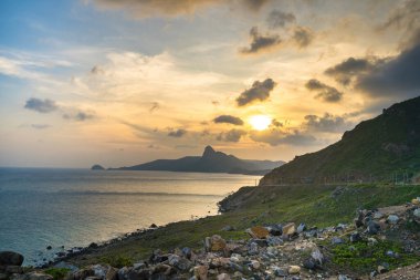 Panoramik Con Dao adası manzaralı, dalgalar, kıyı şeridi, açık gökyüzü ve yol, mavi deniz ve dağ. Bai Nhat Sahili 'nin havadan görünüşü ve sinematik gün batımı..