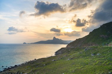 Panoramik Con Dao adası manzaralı, dalgalar, kıyı şeridi, açık gökyüzü ve yol, mavi deniz ve dağ. Bai Nhat Sahili 'nin havadan görünüşü ve sinematik gün batımı..