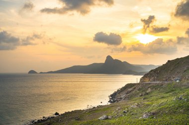 Panoramik Con Dao adası manzaralı, dalgalar, kıyı şeridi, açık gökyüzü ve yol, mavi deniz ve dağ. Bai Nhat Sahili 'nin havadan görünüşü ve sinematik gün batımı..