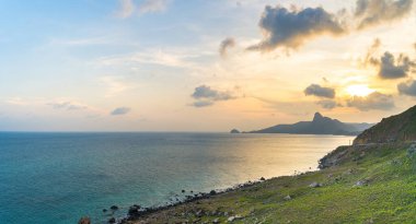 Panoramik Con Dao adası manzaralı, dalgalar, kıyı şeridi, açık gökyüzü ve yol, mavi deniz ve dağ. Bai Nhat Sahili 'nin havadan görünüşü ve sinematik gün batımı..