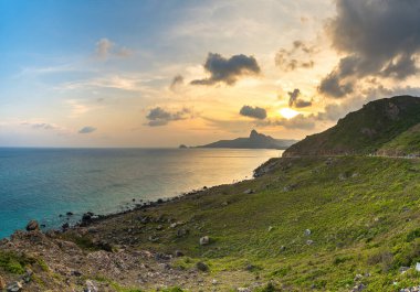 Panoramik Con Dao adası manzaralı, dalgalar, kıyı şeridi, açık gökyüzü ve yol, mavi deniz ve dağ. Bai Nhat Sahili 'nin havadan görünüşü ve sinematik gün batımı..