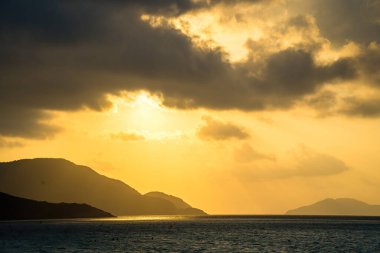 Gün batımında gökyüzü ve bulutların arasında güneş olan sakin bir deniz. Gün batımında gökyüzü ve bulutların arasında güneş olan sakin bir deniz. Meditasyon okyanusu ve gökyüzü arka planı. Huzurlu deniz manzarası. Suyun üzerinde ufuk..