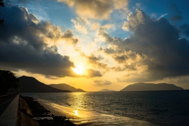 Gün batımında gökyüzü ve bulutların arasında güneş olan sakin bir deniz. Gün batımında gökyüzü ve bulutların arasında güneş olan sakin bir deniz. Meditasyon okyanusu ve gökyüzü arka planı. Huzurlu deniz manzarası. Suyun üzerinde ufuk..