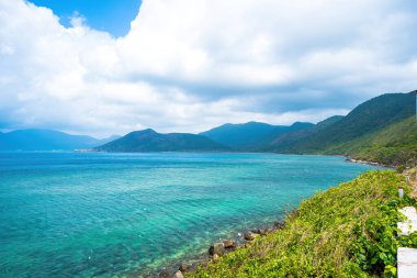 Panoramik sahil kıyısı Con Dao adası yukarıdan, dalgalar, kıyı şeridi, açık gökyüzü ve yol, mavi deniz ve dağ.