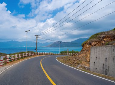Panoramik Con Dao adası manzaralı, dalgalar, kıyı şeridi, açık gökyüzü ve yol, mavi deniz ve dağ. Vietnam 'da bir adada gün batımında gidilecek mükemmel bir yol..