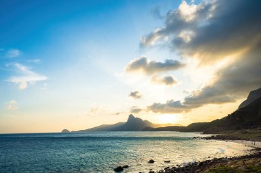 Panoramik Con Dao adası manzaralı, dalgalar, kıyı şeridi, açık gökyüzü ve yol, mavi deniz ve dağ. Bai Nhat Sahili 'nin havadan görünüşü ve sinematik gün batımı..