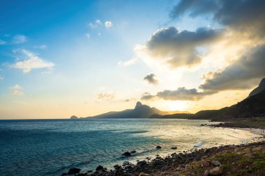 Panoramik Con Dao adası manzaralı, dalgalar, kıyı şeridi, açık gökyüzü ve yol, mavi deniz ve dağ. Bai Nhat Sahili 'nin havadan görünüşü ve sinematik gün batımı..