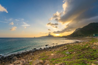 Panoramik Con Dao adası manzaralı, dalgalar, kıyı şeridi, açık gökyüzü ve yol, mavi deniz ve dağ. Bai Nhat Sahili 'nin havadan görünüşü ve sinematik gün batımı..