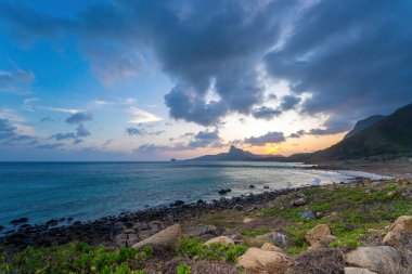 Panoramik Con Dao adası manzaralı, dalgalar, kıyı şeridi, açık gökyüzü ve yol, mavi deniz ve dağ. Bai Nhat Sahili 'nin havadan görünüşü ve sinematik gün batımı..