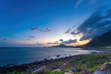 Panoramik Con Dao adası manzaralı, dalgalar, kıyı şeridi, açık gökyüzü ve yol, mavi deniz ve dağ. Bai Nhat Sahili 'nin havadan görünüşü ve sinematik gün batımı..